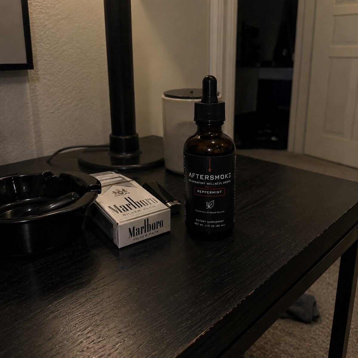 AfterSmoke bottle beside an ashtray and lighter