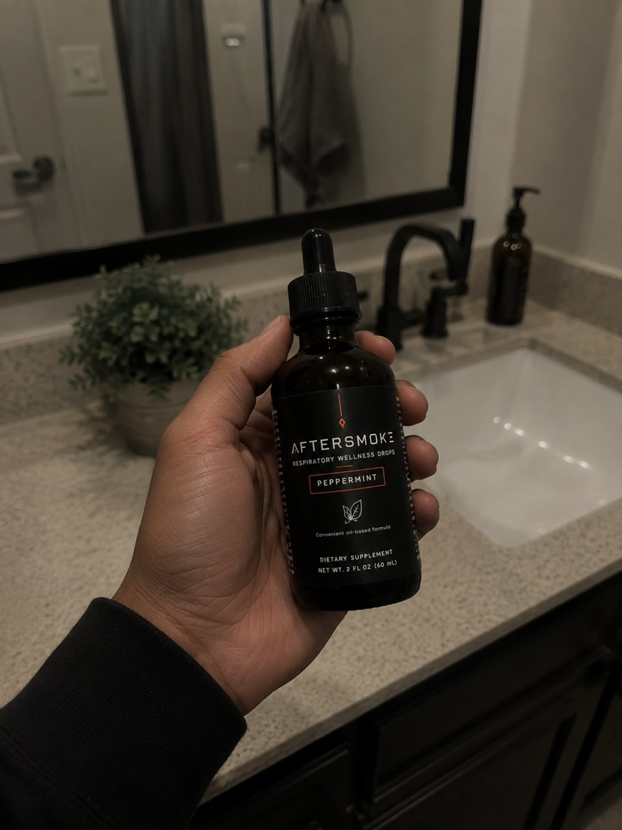 AfterSmoke bottle held in hand in front of a bathroom mirror